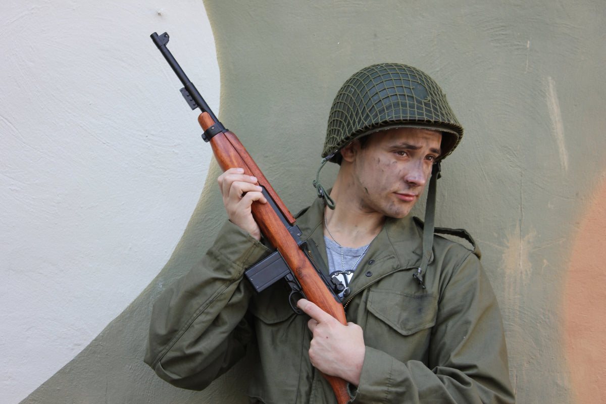 A re-enactor in a WWII US Army uniform holding a replica M1 carbine